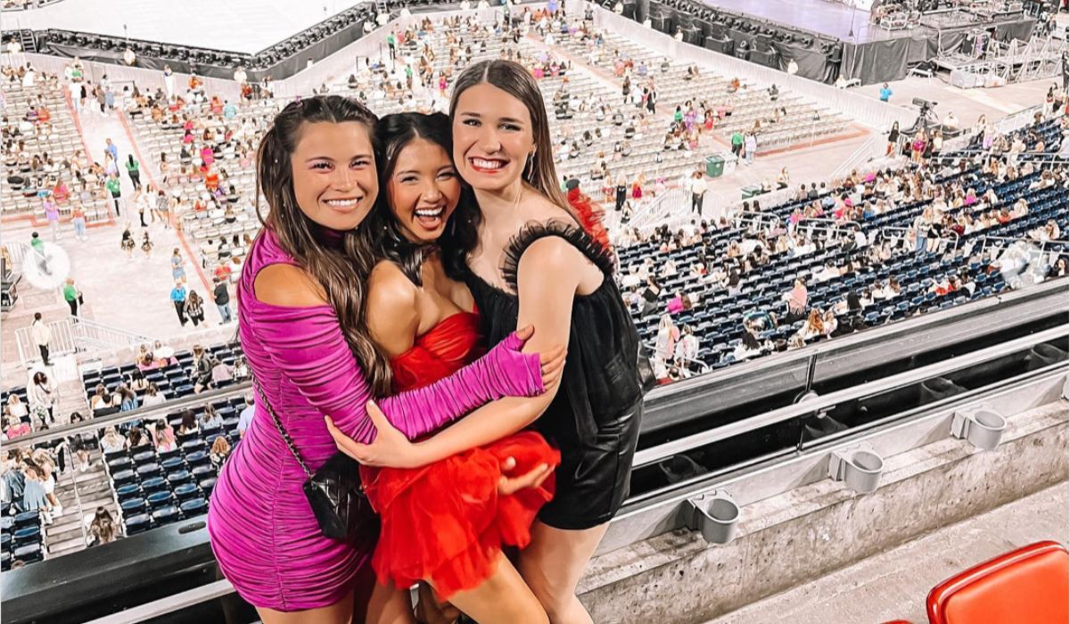 3 Taylor Swift fans posing together in the upper levels of a Taylor Swift concert