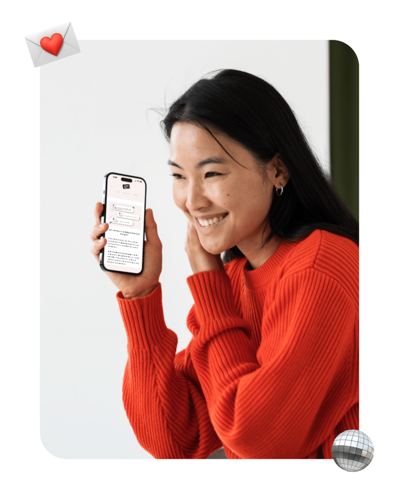 Asian woman in red jumper smiling whilst reading the That Fangirl Life newsletter on her mobile phone.