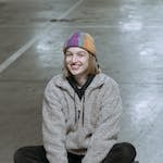 A Woman in Gray Jacket Sitting on Her Skateboard